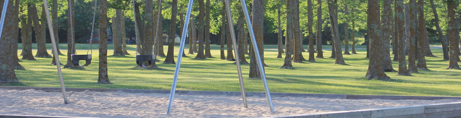 Swings, under the shade of the trees at Point Park in Fort Frances